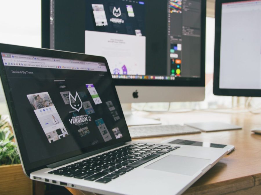 Birou de designer cu laptop și monitoare care afișează programe de design