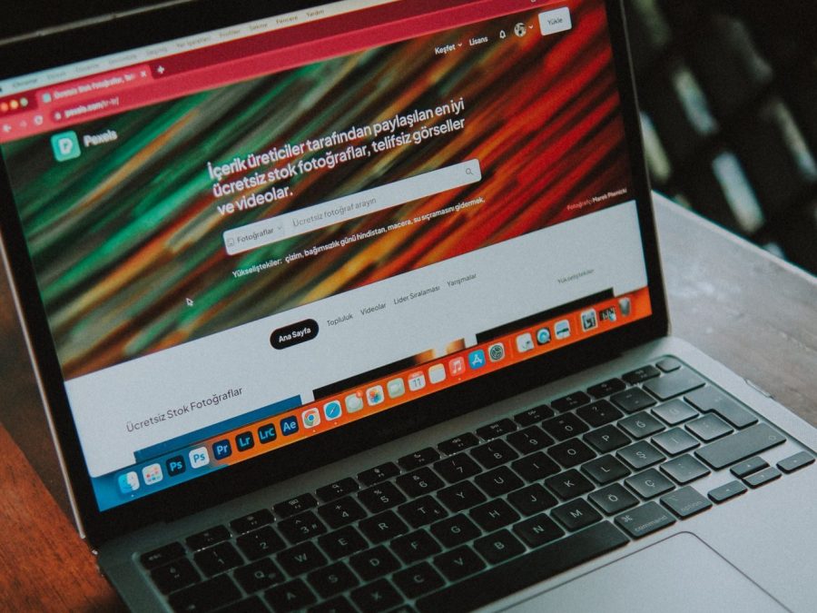 Laptop cu un site deschis, așezat pe o masă de lemn lângă fereastră