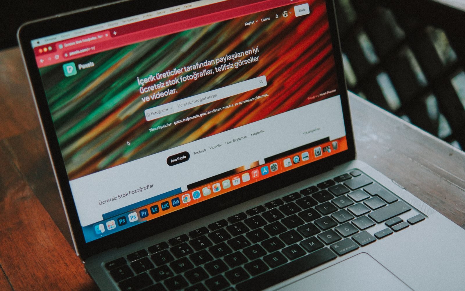 Laptop cu un site deschis, așezat pe o masă de lemn lângă fereastră