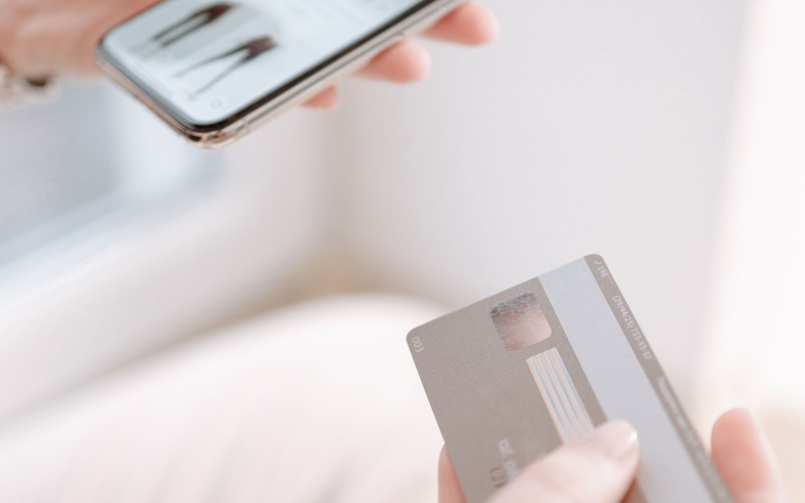 Mâini care țin un smartphone și un card pentru cumpărături online