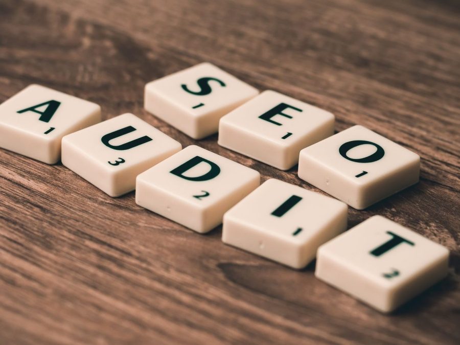Litere de Scrabble care formează „SEO Audit”, pe o masă de lemn