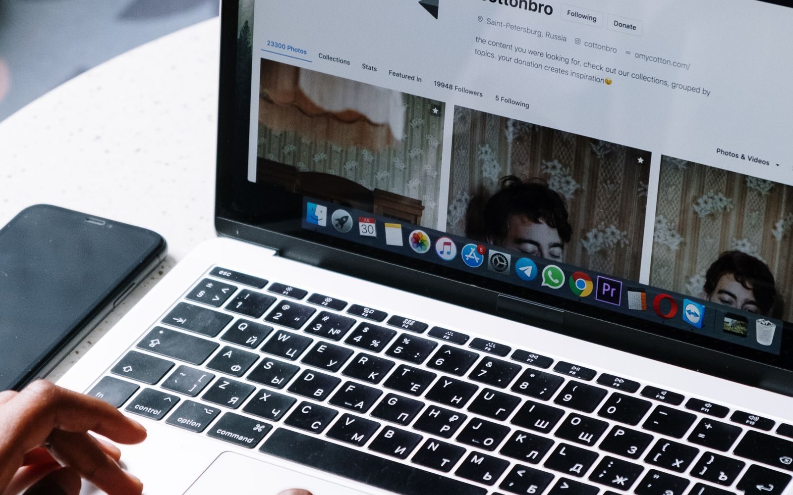Persoană care lucrează pe laptop la o masă de cafenea