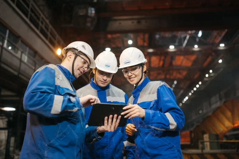 Ingineri care discută un proiect pe o tabletă, într-o fabrică