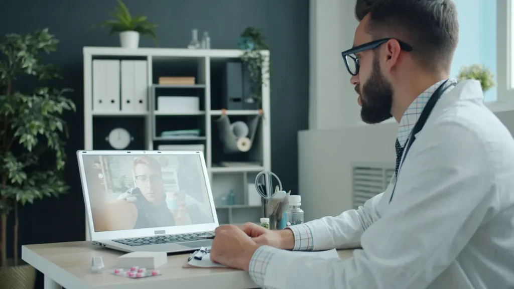 Medic care ține o consultație video cu un pacient, pe laptop