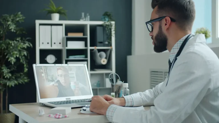 Medic care ține o consultație video cu un pacient, pe laptop