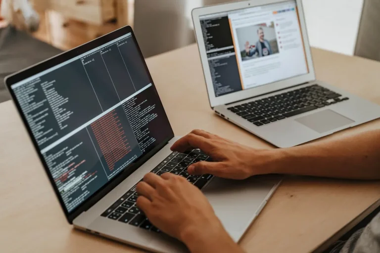 Dezvoltator care lucrează pe un laptop, cu cod pe ecran