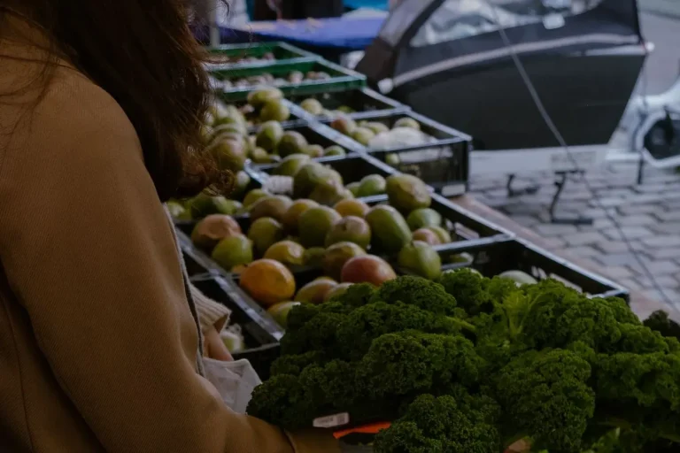 Femeie care alege legume proaspete la o piață în aer liber