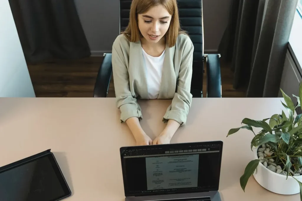 Femeie la un birou, cu laptop deschis, într-un interviu de angajare