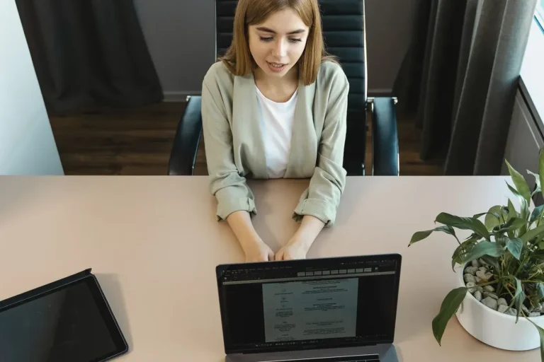 Femeie la un birou, cu laptop deschis, într-un interviu de angajare