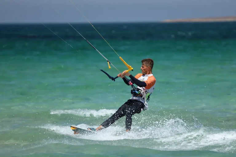 Practicant de kitesurfing, în plin salt, deasupra valurilor