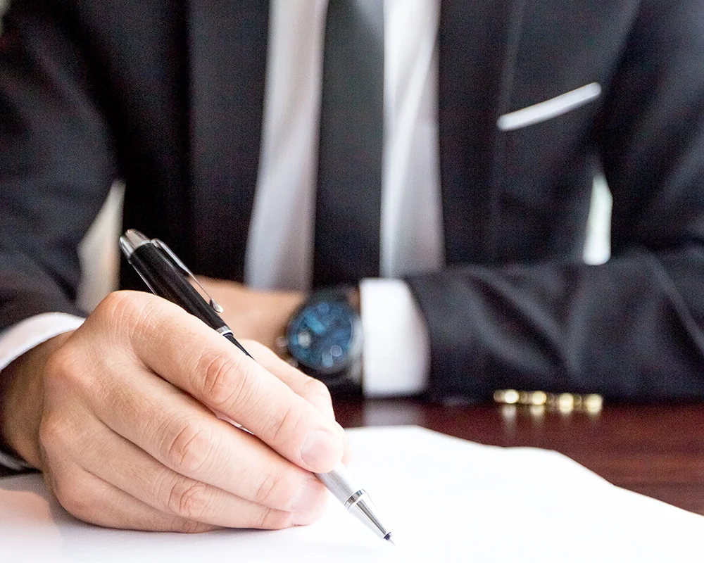 Mâna unui avocat semnând un document, la un birou